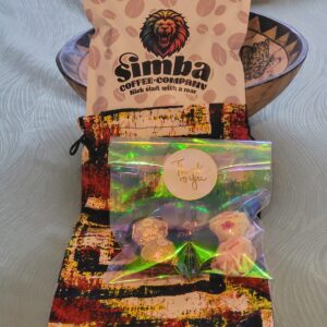 A colorful bag of Simba Coffee Company coffee sits next to a treat bag labeled "Thank You," containing chocolates and candies, on a patterned tablecloth.